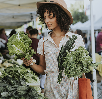 Young woman shopping for vegetables in a farmers market.