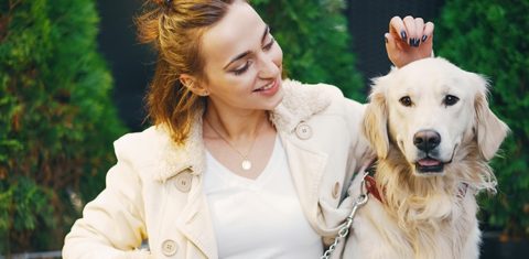 woman with jacket in a park with her dog