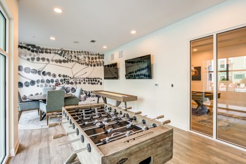 Indoor clubhouse area with foosball table, shuffleboard, lounge seating and wood-style flooring