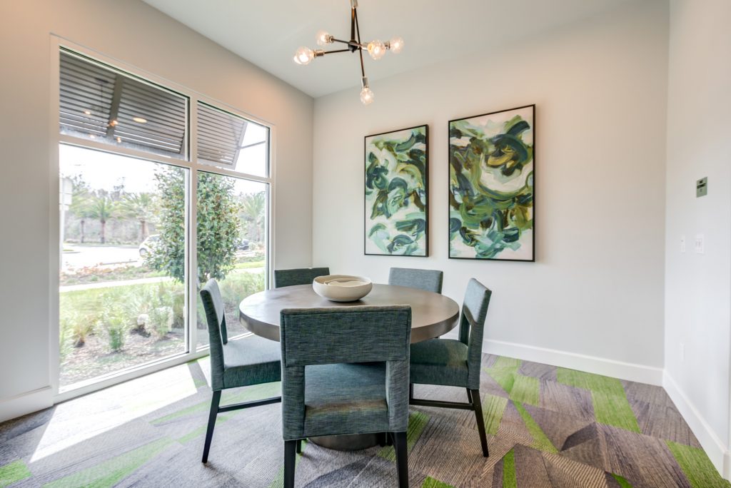 Small clubhouse room with dining seating and windows to outdoor garden