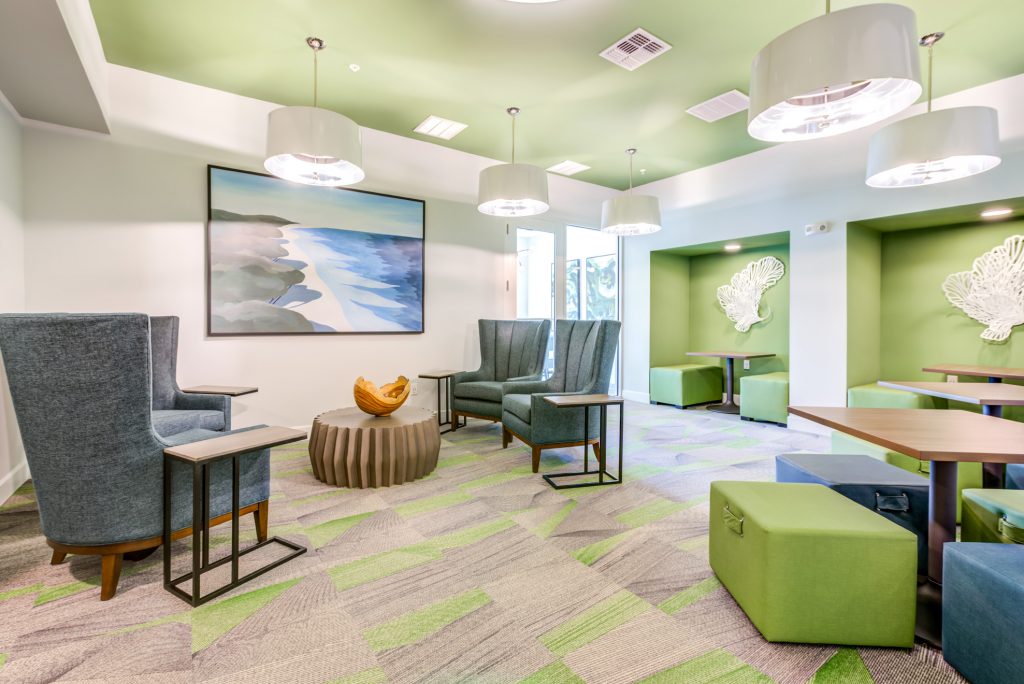 Clubhouse lounging area with seating, ocean decor, and carpet flooring