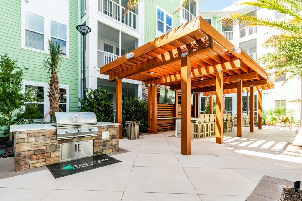 Outdoor clubhouse area with shaded seating and grilling
