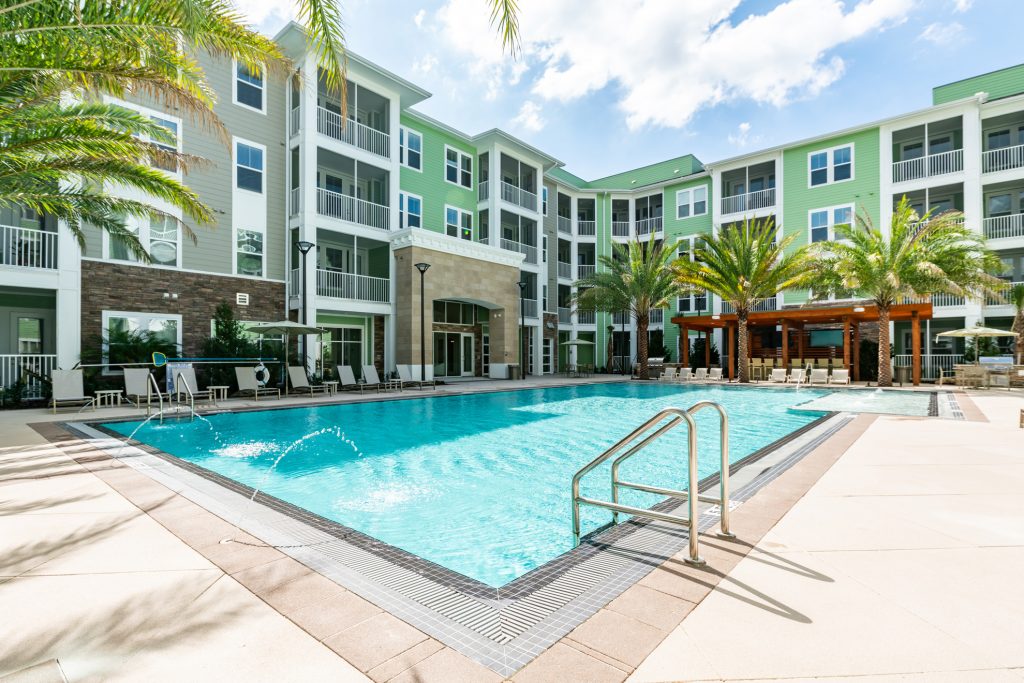 Outside pool area with tropical landscaping, umbrellas and sun beds