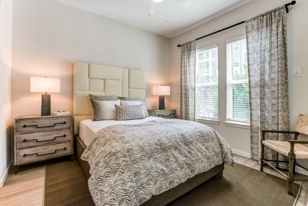 Bedroom with warm light lamps, windows, and wood-style flooring